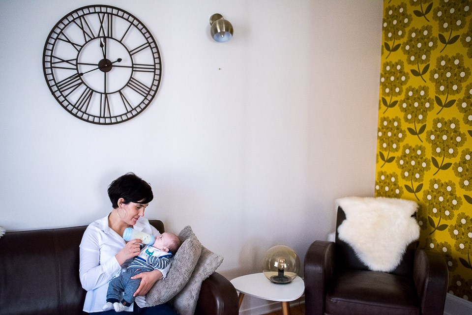 maman donne le biberon à bébé sous une énorme horloge